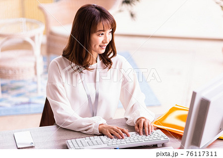 明るい室内でデスクワーク中の女性 76117311