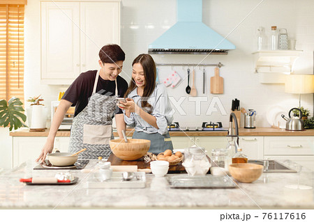 A couple uses their smart phone to take a picture while admiring his wife's cooking work With a happy face in an atmosphere of love 76117616