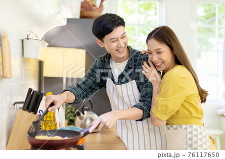 Portrait young couple in love helping to cook In a romantic atmosphere at home and looking at camera with smile face. 76117650