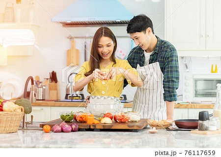 A couple breaks an egg to make a morning omelet at home. Romantic time For a newly married couple. 76117659