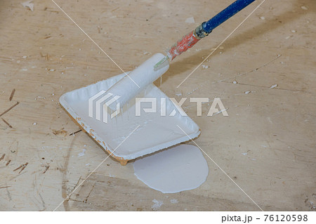 Roller is wetted in a liquid primer in a plastic container before painting the walls with paint Roller is wetted in a liquid primer in a plastic container before painting the walls with paint 76120598