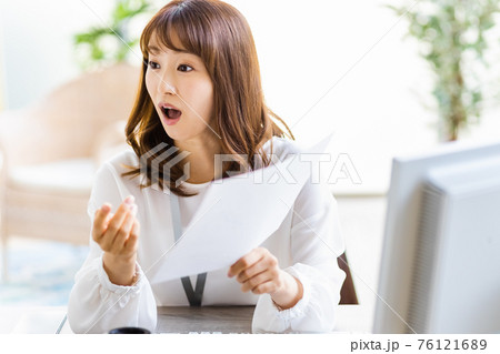デスクワーク中にフレーム外の人物と話をする女性 76121689