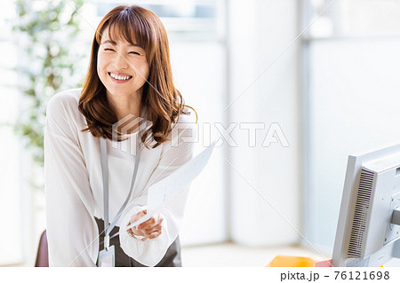 デスクワーク中にフレーム外の人物と話をする女性 デスクワーク中にフレーム外の人物と話をする女性 76121698