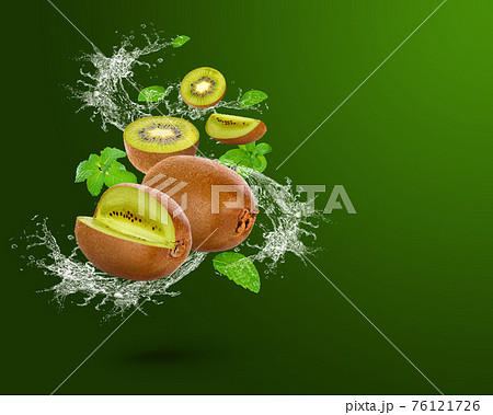 Water splash on fresh Kiwi with mint isolated on green background.  76121726