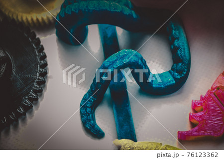 Many bright multi-colored objects printed on 3d printer lie on flat surface Many bright multi-colored objects printed on 3d printer lie on flat surface 76123362
