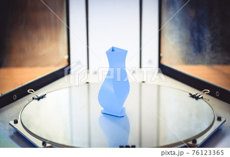Bright blue object printed by 3d printer on 3d printer inside. Bright blue object printed by 3d printer on 3d printer inside. 76123365