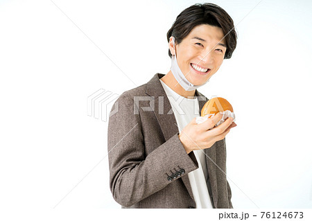ウレタンマスクを顎にずらしてハンバーガーを食べるカジュアルなビジネスマン 76124673