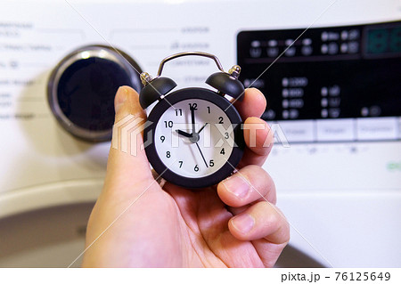 Washing clothes, alarm clock in hand selective focus. 76125649