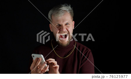 Shocked happy smiling winning of man while browsing on smartphone, feeling happiness, fun, enjoyment Shocked happy smiling winning of man while browsing on smartphone, feeling happiness, fun, enjoyment 76125977