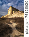 Beautiful white mountain peak lit by sun. White clouds and blue sky on background. Epic rock formation 76126020