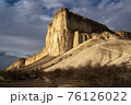 Beautiful white mountain peak lit by sun. White clouds and blue sky on background. Epic rock formation 76126022
