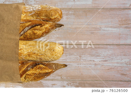 French traditional baguettes in paper bags on wooden table background. French traditional baguettes in paper bags on wooden table background. 76126500