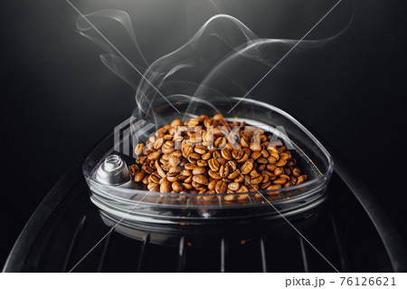 fresh roasted coffee beans with smoke in coffeemaker bean container, close-up view fresh roasted coffee beans with smoke in coffeemaker bean container, close-up view 76126621