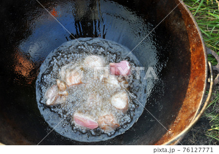 Cooking meat in a cauldron on fire. 76127771