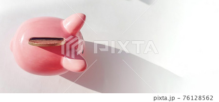 Banner Top view over pink piggy bank with slot and inserted coin, on white background, savings and investment concept, copy space, place for text Banner Top view over pink piggy bank with slot and inserted coin, on white background, savings and investment concept, copy space, place for text 76128562