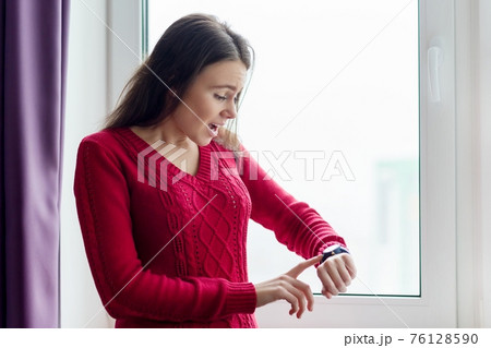 Young woman checking the time on her watch 76128590