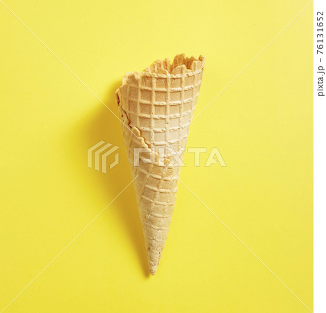 Sweet wafer cone on yellow background 76131652