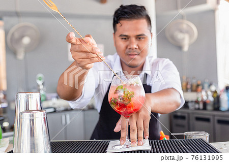 Bartender is making cocktail at counter bar. 76131995
