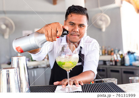Bartender is making cocktail at counter bar. Bartender is making cocktail at counter bar. 76131999