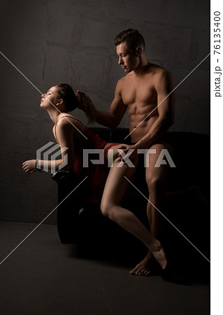 Man and woman in underwear play bdsm game on black sofa 76135400