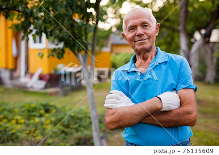 Elderly gardener posing in his garden Elderly gardener posing in his garden 76135609
