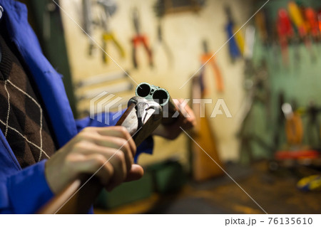 Break-action of horizontal double-barreled shotgun in hands of gunsmith 76135610