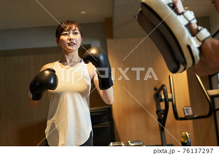 パーソナルトレーナーからキックボクシングを習うアジア人女性 76137297