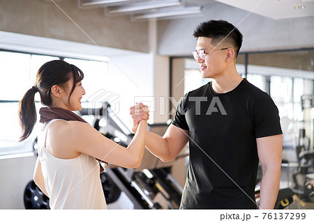 トレーニングジムで手を組むアジア人カップルの写真素材