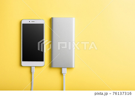 Smartphone charging with power bank by wire on yellow background. 76137316