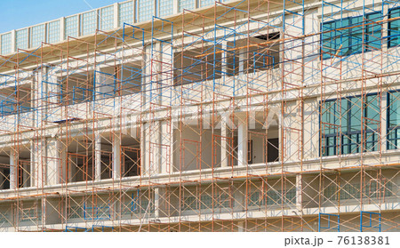 Scaffolding of house building. Lattice mast, cables or poles in busy industrial under construction site with cranes. Steel or metal structure. Development stucture architecture. Real estate. 76138381