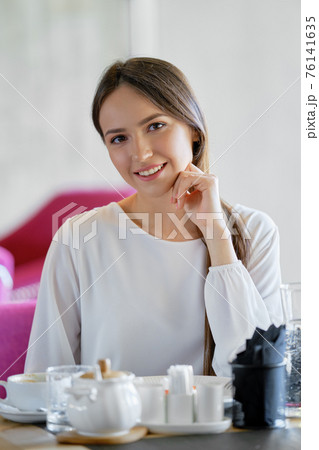 Beautiful woman sitting in cafe and eating cake during break 76141635