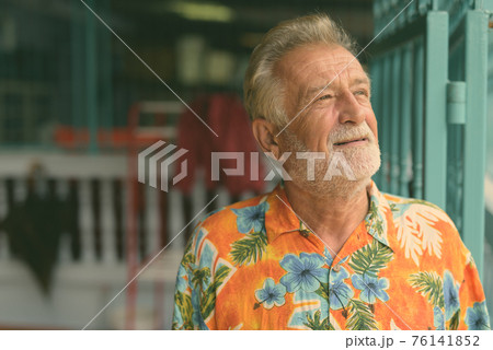 Close up of happy senior bearded tourist man smiling and thinking while looking up ready for Close up of happy senior bearded tourist man smiling and thinking while looking up ready for 76141852