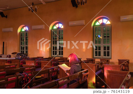 Asian woman praying in empty christian church with cross, architecture design. Religious beliefs. Catholic religion. Jesus worship. People lifestyle. 76143119