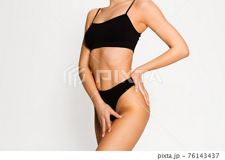 Beautiful female body in black underwear over white background. 76143437