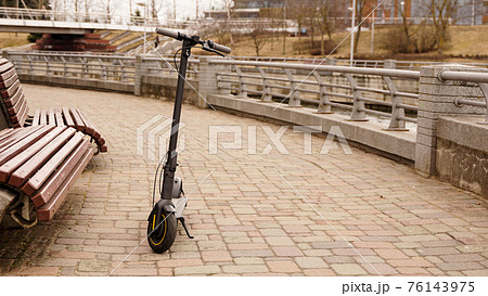 Electric scooter in the park next to the bench. Photos without people. 76143975