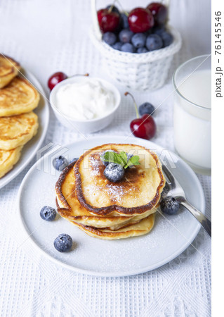 Cottage cheese pancakes (syrniki). Homemade cheesecakes from cottage cheese with sour cream, berries and milk. Traditional Russian dish. Close-up. 76145546
