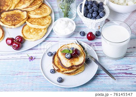 Cottage cheese pancakes (syrniki). Homemade cheesecakes from cottage cheese with sour cream, berries and milk. Traditional Russian dish. Close-up. 76145547