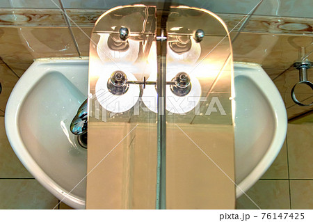 A mirror with shelf over sink and under lamp in a bathroom. A mirror with shelf over sink and under lamp in a bathroom. 76147425