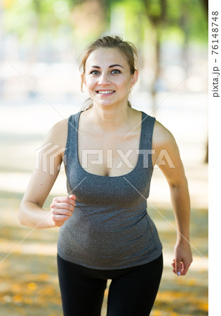 happy female in sportwear running in the sunny park happy female in sportwear running in the sunny park 76148748