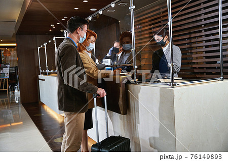 Guests filling in the registration form at the reception desk 76149893