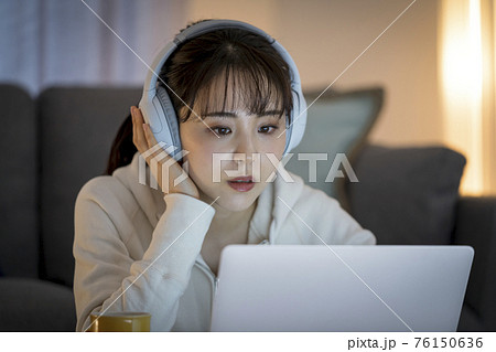 ヘッドホンをつけてノートパソコンの画面を見る女性 ヘッドホンをつけてノートパソコンの画面を見る女性 76150636