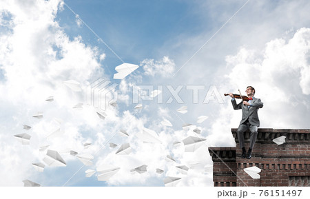 Handsome businessman play his melody and paper planes fly around Handsome businessman play his melody and paper planes fly around 76151497