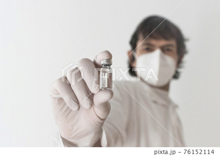 Doctor holding a vaccine bottle and syringe, beginning of worldwide mass vaccination for coronavirus COVID-19, influenza or flu, world immunization concept. Selective focus Doctor holding a vaccine bottle and syringe, beginning of worldwide mass vaccination for coronavirus COVID-19, influenza or flu, world immunization concept. Selective focus 76152114
