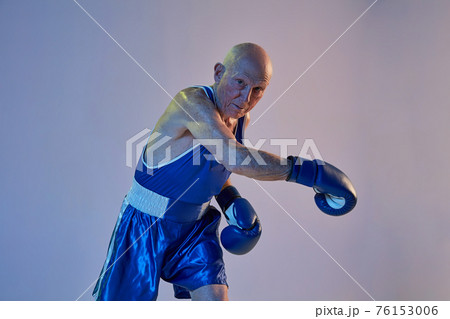 Senior man wearing sportwear boxing isolated on gradient studio background in neon light. Concept of sport, activity, movement, wellbeing. Copyspace, ad. 76153006