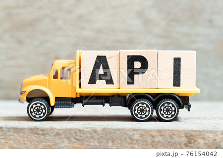 Toy truck hold alphabet letter block in word API (Abbreviation of Application programming interface or Active pharmaceutical ingredient) on wood background 76154042