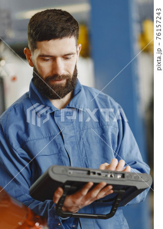 ar mechanic with a tablet near car in work clothes 76157243