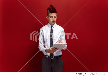 Elegant punk with tablet against of red background 76158305
