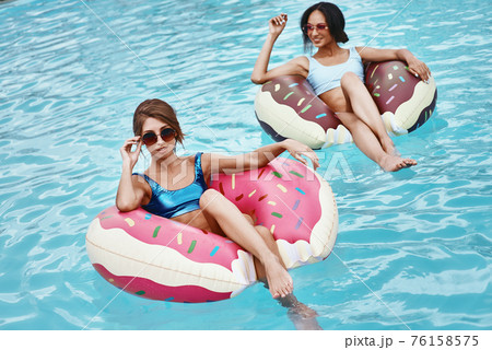 Swimming is my sport, The pool is my Home, The water is my friend. Girls relaxing with inflatable rings in the shape of donuts Swimming is my sport, The pool is my Home, The water is my friend. Girls relaxing with inflatable rings in the shape of donuts 76158575