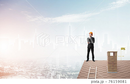 Engineer man standing on roof and looking away. Mixed media 76159081