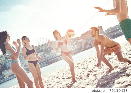 Time with friends. Group of young people playing volleyball on the beach Time with friends. Group of young people playing volleyball on the beach 76159433